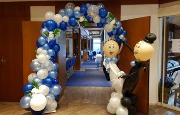 Ein Ballonbogen im Organic Stil passend zum Herz, mit einem Ballon-Brautpaar welches den Bogen gemeinsam hält. Ballondekoration für eine Hochzeit